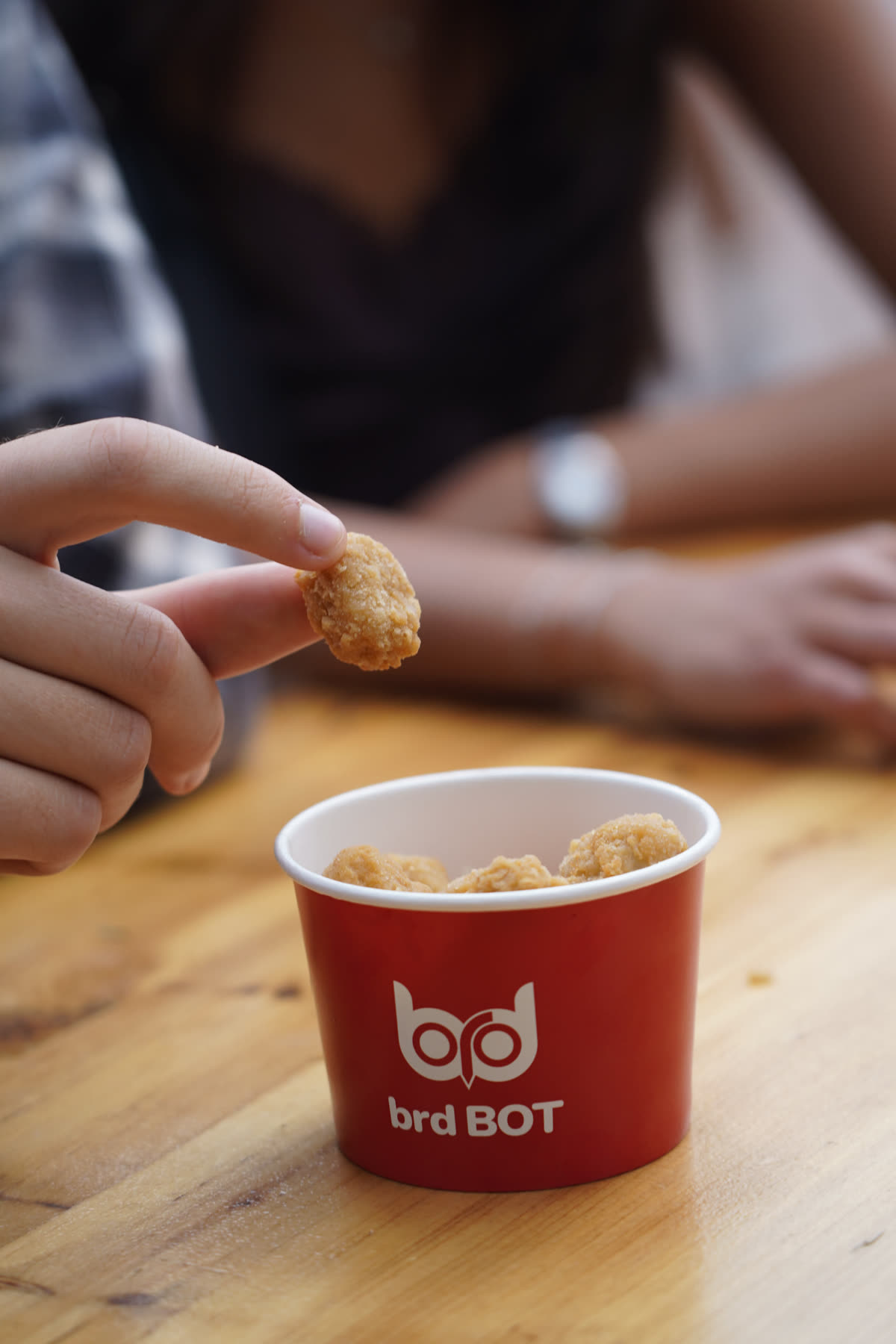 A crispy chicken bite above a brd BOT cup